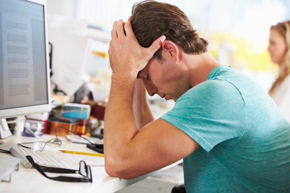 employee who is upset and holding his head at work
