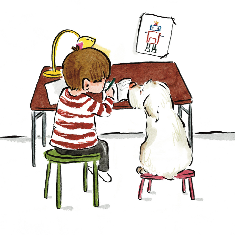 Young boy with brown hair and red striped shirt writes in a journal at his desk with his Clumber spaniel sitting next to him