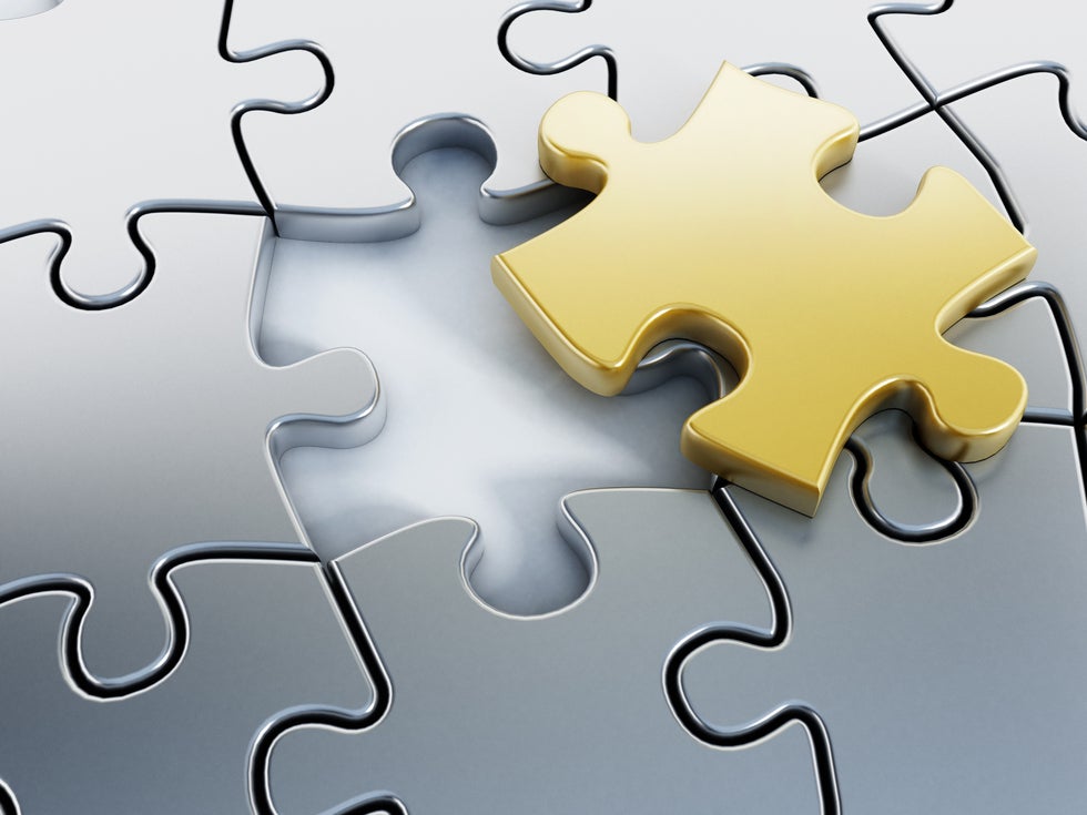 Gold puzzle piece that is not assembled into puzzle but is sitting atop area designed for its insertion, in a puzzle that is otherwise completed with silver pieces.