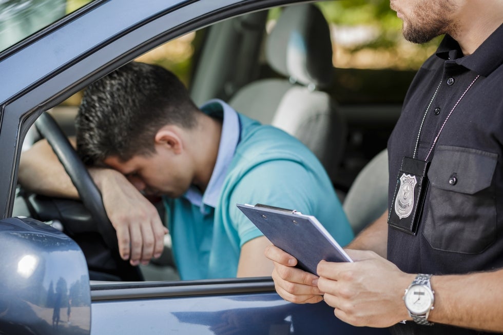 A photo of a frustrated driver resting his head on his steering wheel during a traffic stop.