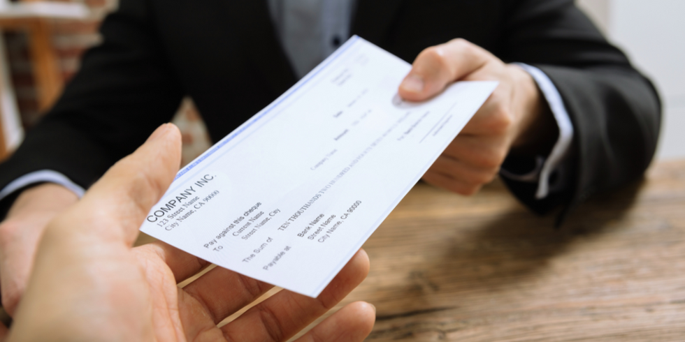 A photo of a person passing a personal check to another person.