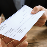 A photo of a person passing a personal check to another person.
