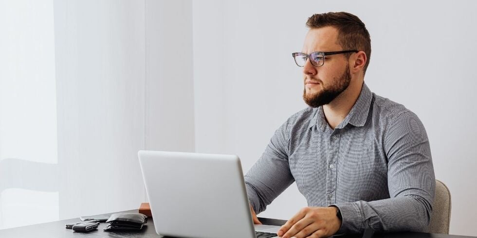 A man seated at a desk with a laptop computer. 