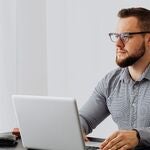A man seated at a desk with a laptop computer. 