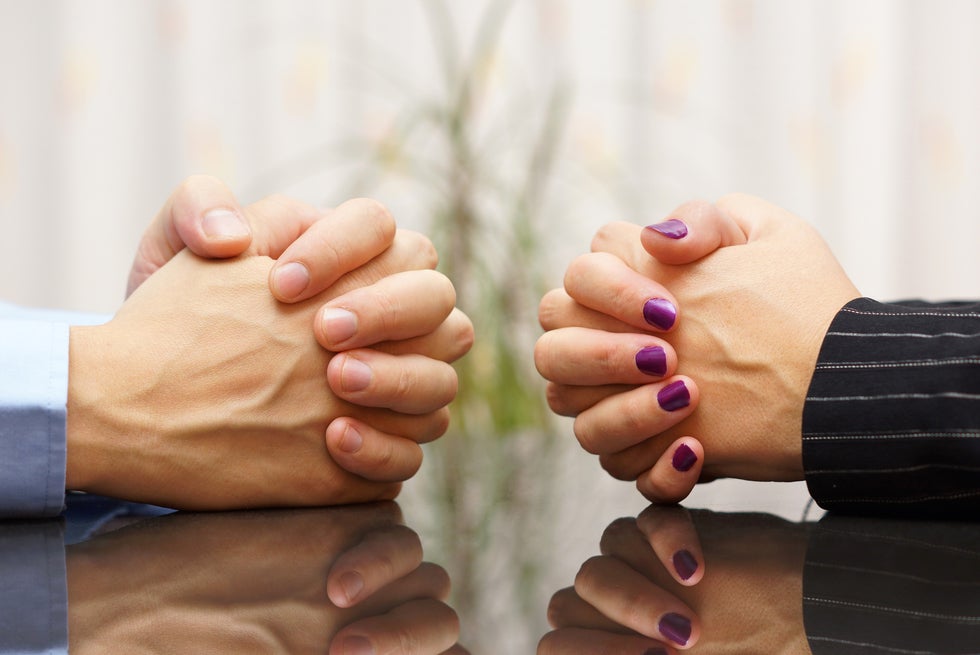 two sets of clasped hands of people facing each other