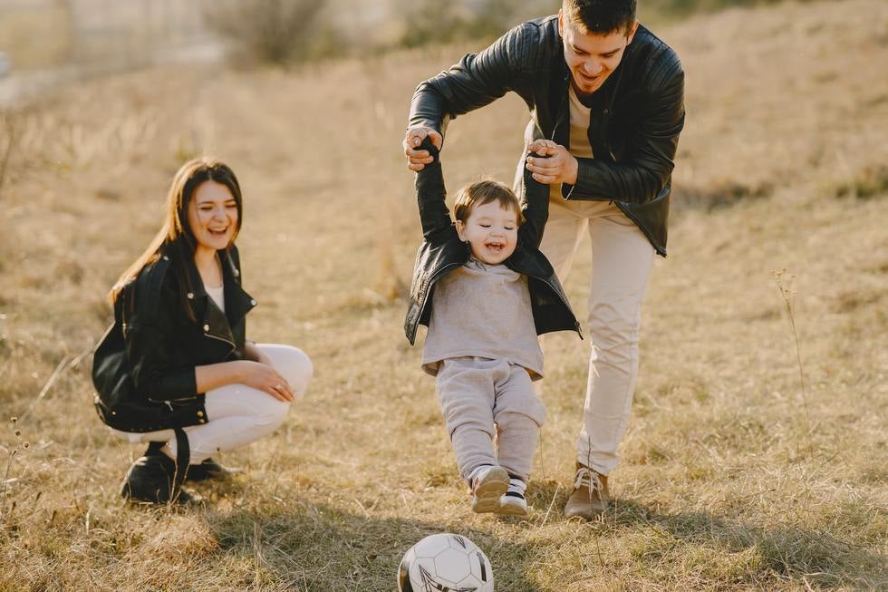 mom and dad playing ball with toddler boy