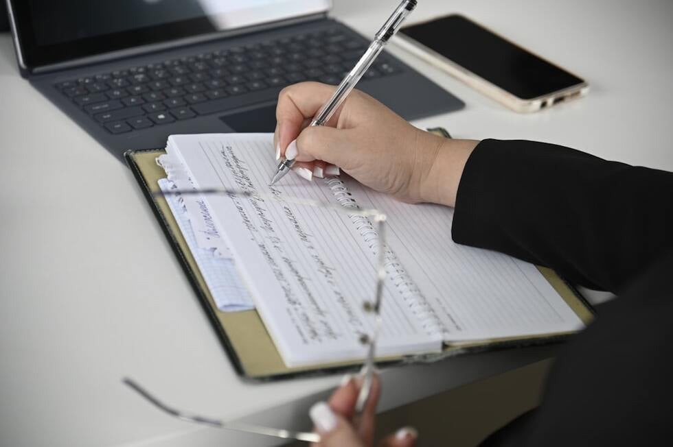 person taking notes and organizing documents at a desk - wrongful termination at will employment