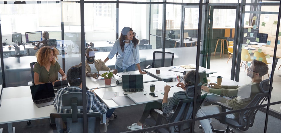 "Young people sitting around a desk with a testimonial advertising attorney planning a testimonial advertising campaign."