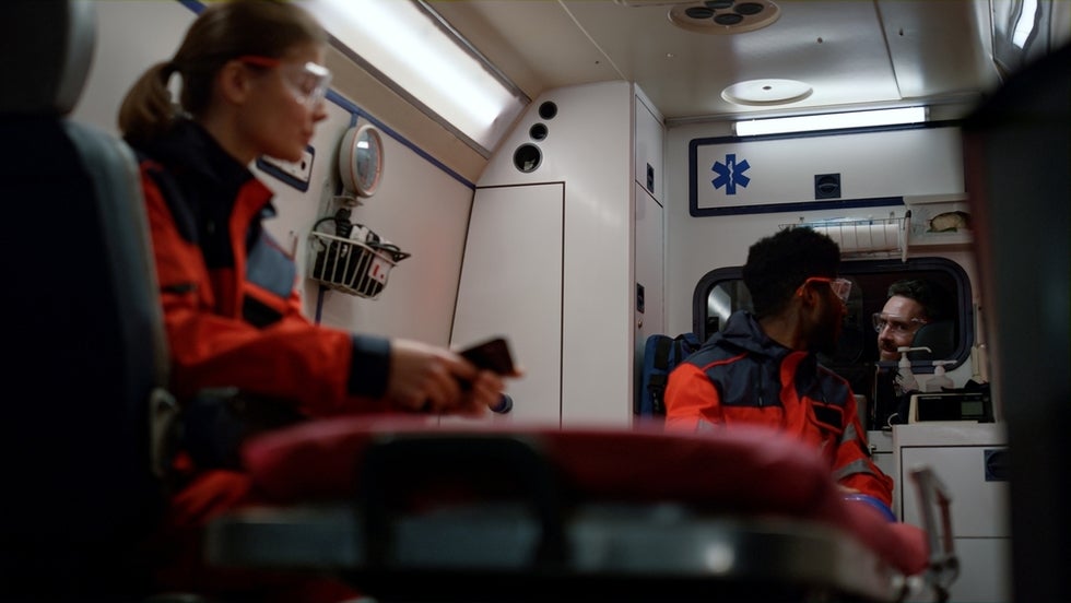 Paramedic in ambulance holding smartphone.