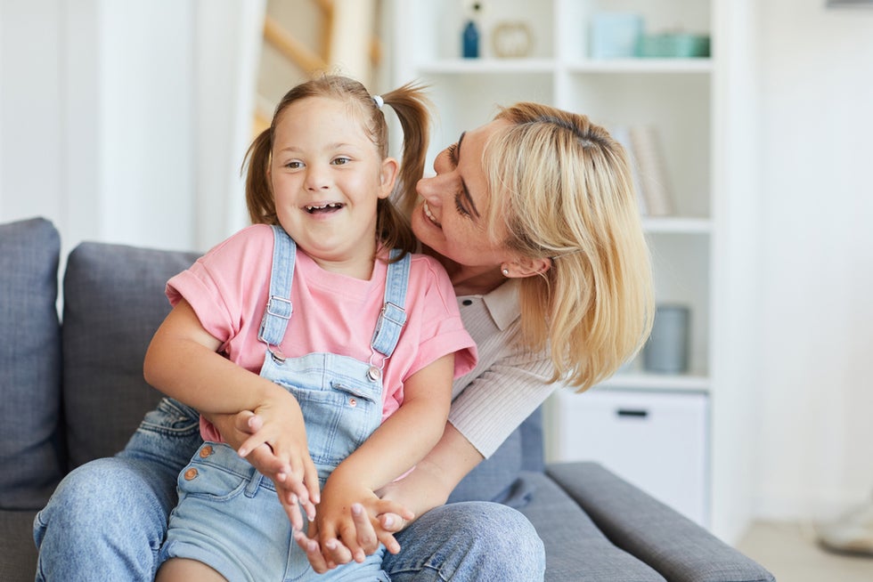 Mother embracing her child with Down Syndrome on sofa