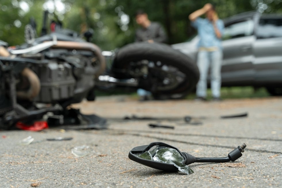 A person stands in the background of a motorcycle crash scene. Should I get a lawyer for a motorcycle accident in Los Angeles?