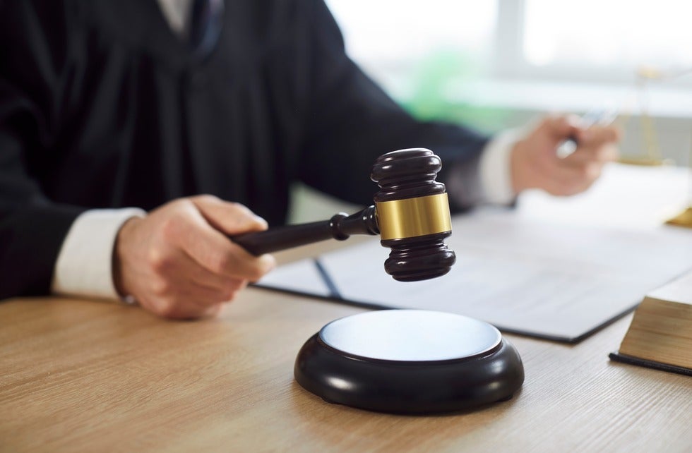 Man judge knocking gavel wearing robe having court verdict sitting at the desk on workplace in courtroom
