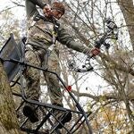 Man holding a hunting gear standing on a tree stand - smaller image