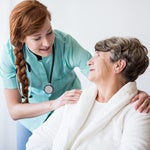 a nurse and an elderly woman smiling at each other