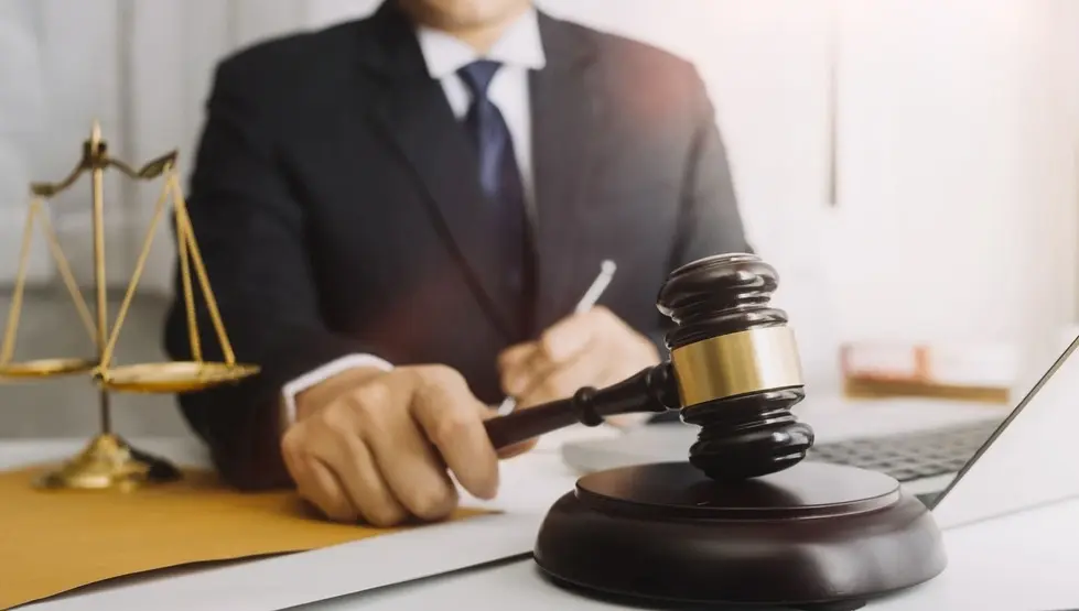 Lawyer in suit at desk with a gavel and scales of justice, representing legal services offered in Monmouth Beach, NJ.