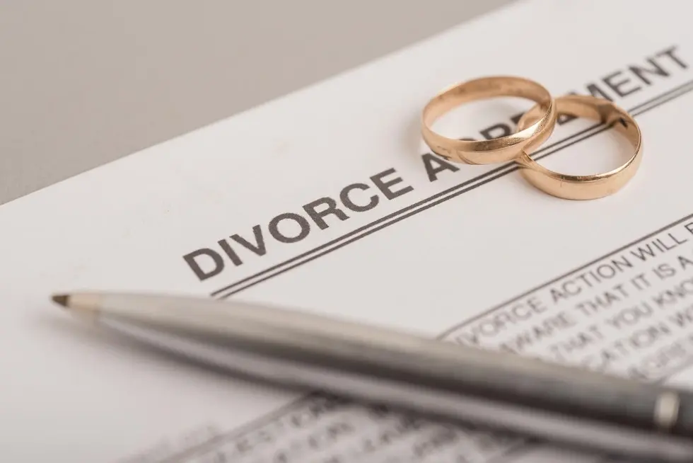 Wedding rings on a divorce agreement form, highlighting family law and legal services in Monmouth Beach, NJ.