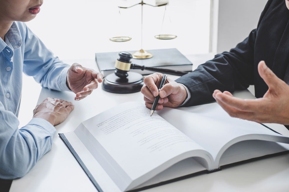 A lawyer and client discuss a contract during a meeting, representing legal services offered in Manasquan, New Jersey.