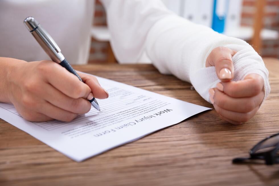 Injured person filling out work injury claim form, representing personal injury legal help in Surf City, NJ