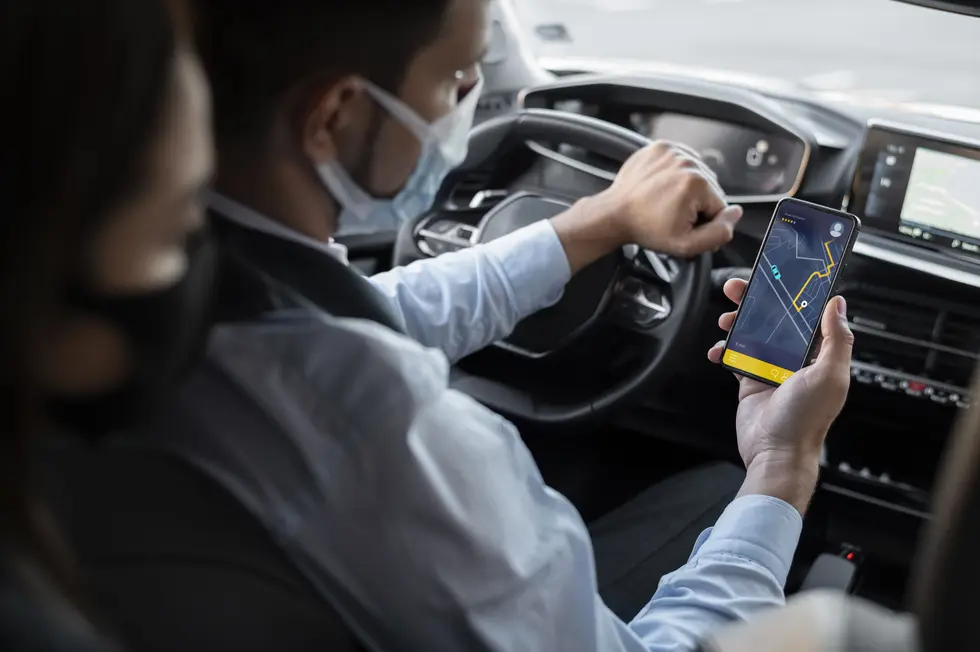 Inside a car, a man with a face mask uses his phone, highlighting a ride share scenario in New Jersey.