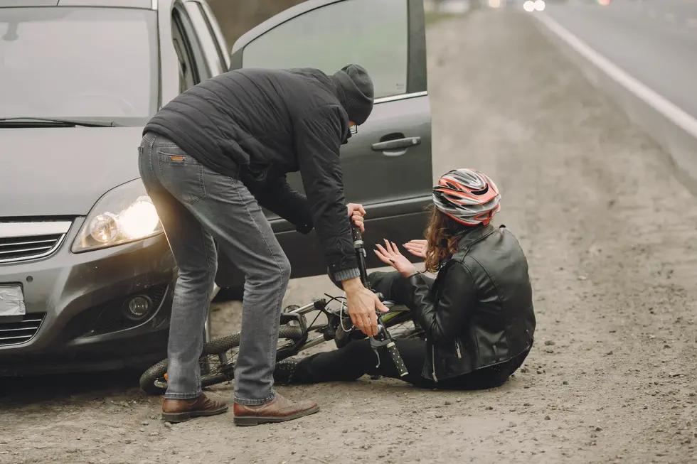  A man assists a woman on the ground near a car, highlighting a scene after a cyclist was hit in New Jersey.