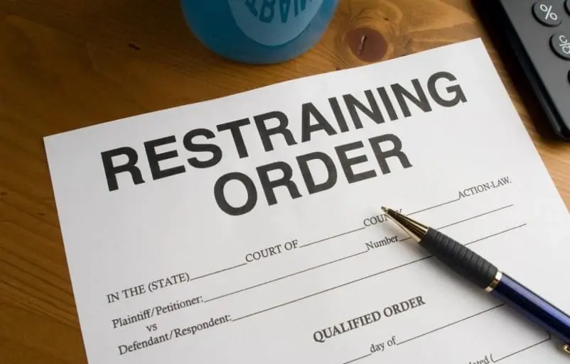 Restraining order document and pen representing legal disputes and financial disclosure issues in New Jersey divorce cases