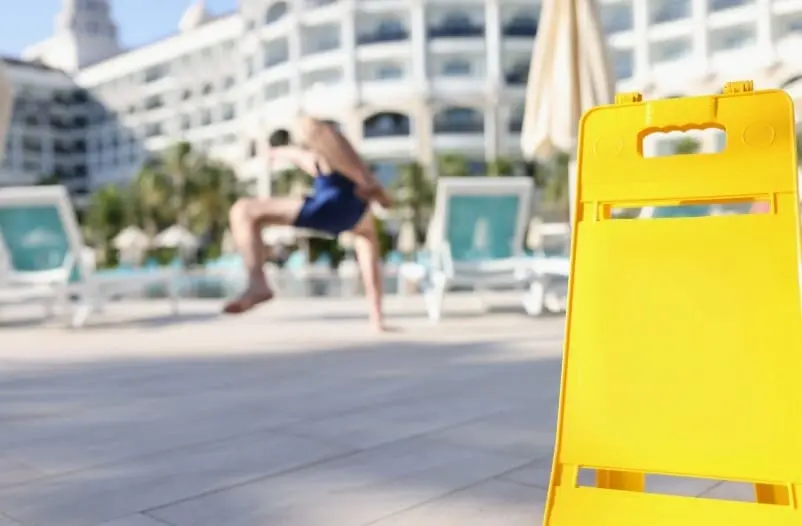 Wet floor warning sign near hotel pool area representing Jersey Shore slip and fall accident claims