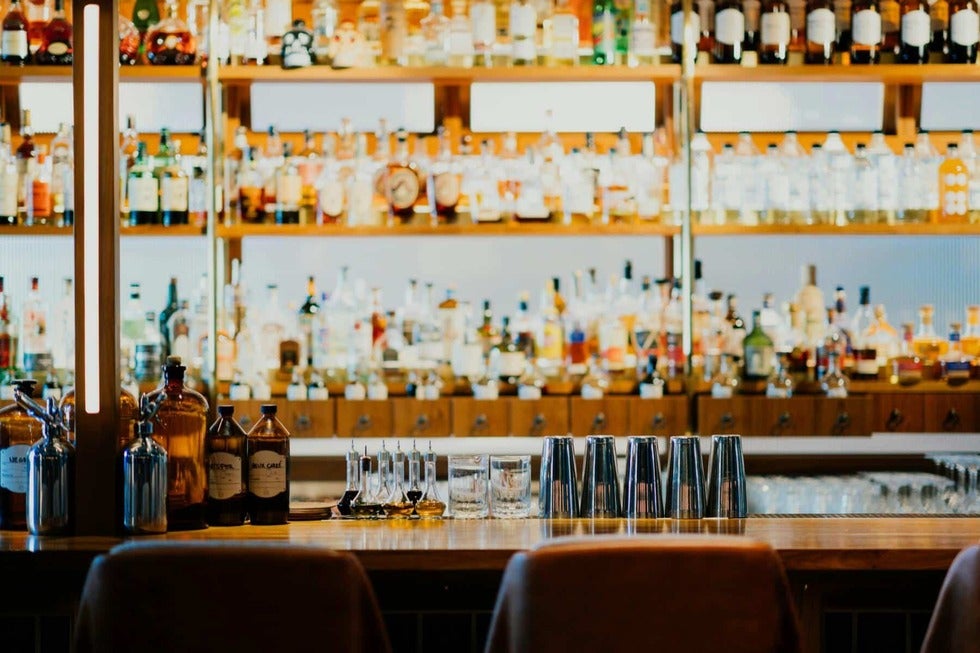 Well-stocked bar with shelves of liquor bottles, representing legal counsel for liquor manufacturing license applicants in New Jersey