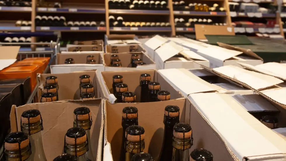 Cardboard boxes of corked liquor bottles in a wholesale warehouse, illustrating the wholesale liquor license distribution process