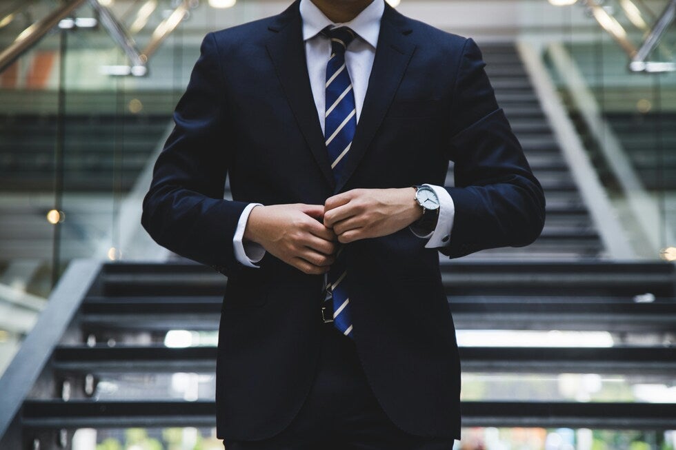 Attorney in a dark suit buttoning jacket, representing legal defense for assault by auto charges in New Jersey