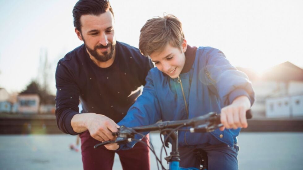 A father is teaching his son to ride a bike during his time-sharing schedule.