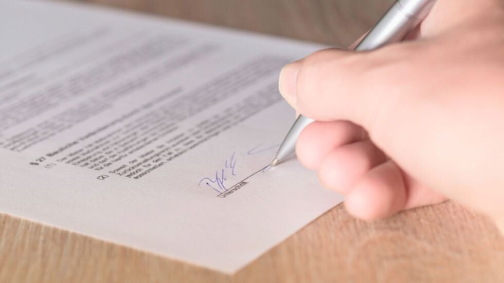 A hand signing a prenuptial or postnuptial agreement in Miami.