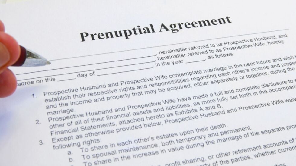 A hand about to fill out a Miami prenuptial or postnuptial agreement.