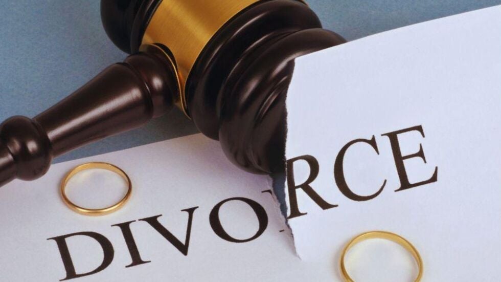 Close-up of a judge’s gavel resting on a torn divorce document with two gold wedding rings on either side, symbolizing a marital breakup and legal divorce proceedings in Miami for professional athletes.