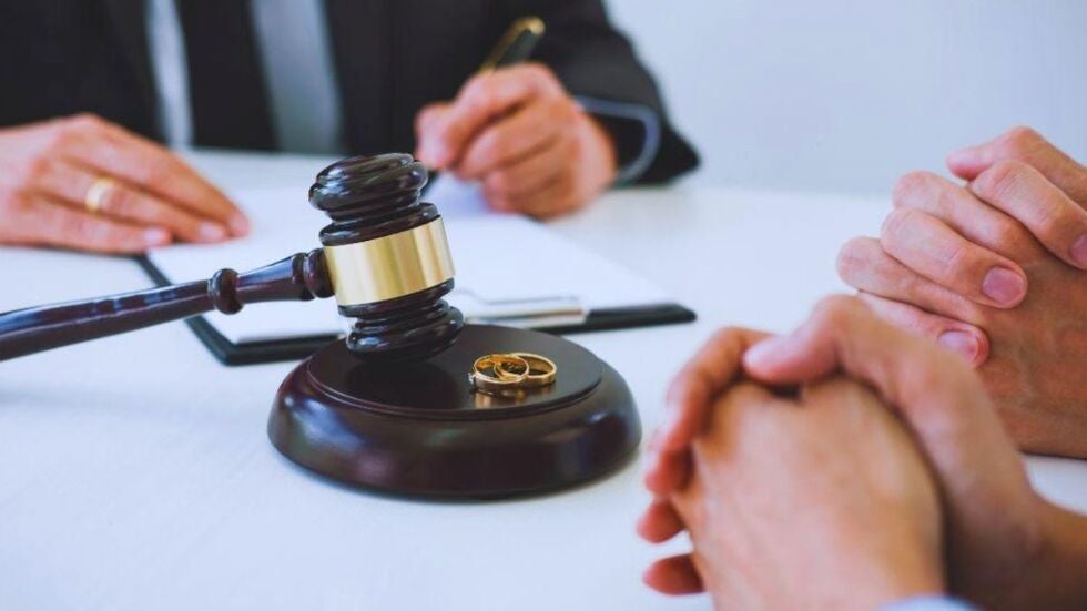 Close-up of a divorce lawyer meeting with a couple at a conference table, with a judge’s gavel and two gold wedding rings in focus, symbolizing a Miami attorney guiding professional athletes through divorce.