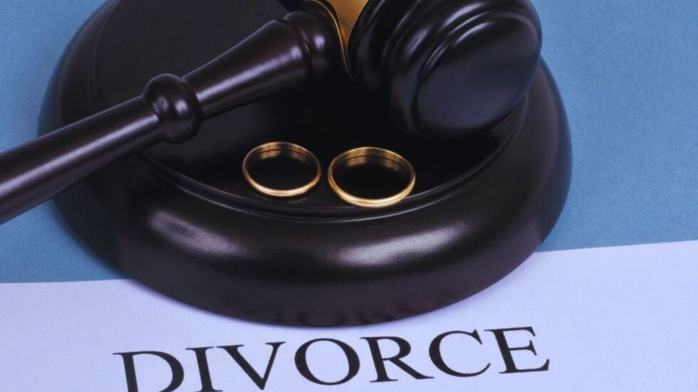 Judge’s gavel resting on a sound block with two wedding rings beside it, placed over a document labeled “Divorce,” symbolizing divorce and business ownership legal matters.