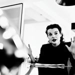 Woman sitting in the conference room of an office speaking to a group of people