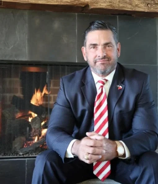 Houston criminal defense attorney Sam R. Cammack III seated in front of a fireplace.