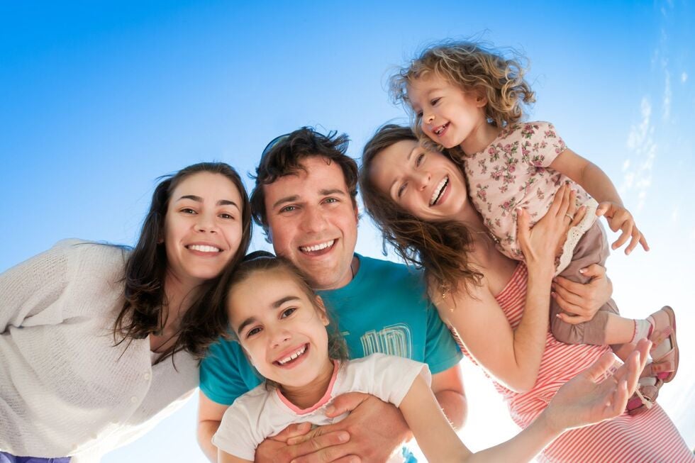 A family is posing for a picture with a blue sky in the background.