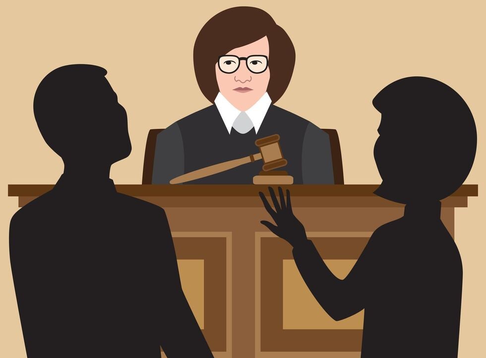 A man and a woman are sitting in front of a judge in a courtroom.