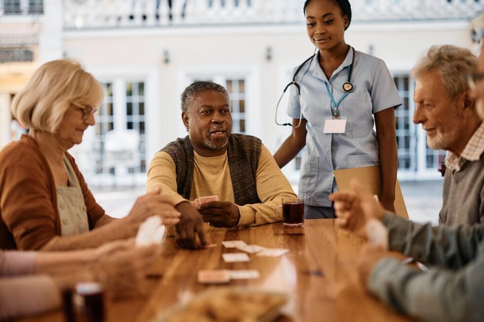 Multiracial group of senior friends playing cards in nursing home.