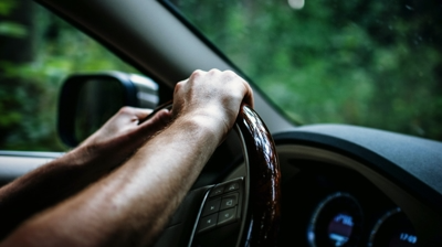 Close up of a driver's hands on the steering wheel of their car