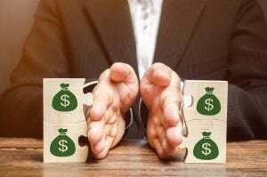 Businessman separates the wooden puzzle with a picture of money.