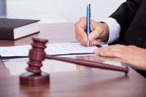 Male Judge Writing On Paper In Courtroom