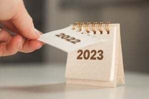 a woman's hand turns over a calendar sheet. year change from 2022 to 2023.