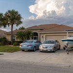 Two cars and a boat on a trailer in a Punta Gorda driveway.