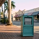 Newspaper vending box on a downtown Fort Myers sidewalk at sunrise, representing the published notice to creditors that opens a Florida formal administration
