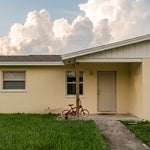 Child’s bicycle leaning on the front porch of a Bonita Springs home, representing the minor child who makes a Florida homestead impossible to devise