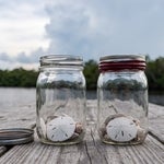 Two glass jars on a riverside picnic table in Estero, one open and one sealed, representing a revocable and an irrevocable trust in Florida