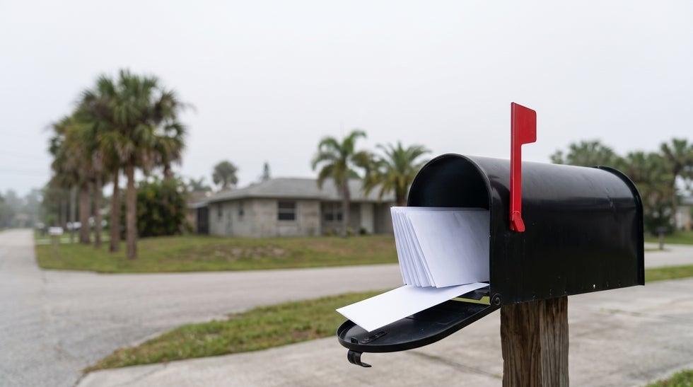 Residential mailbox in North Fort Myers with its flag up and a bundle of blank envelopes inside, representing creditor claims arriving after a death in Florida
