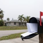 Residential mailbox in North Fort Myers with its flag up and a bundle of blank envelopes inside, representing creditor claims arriving after a death in Florida
